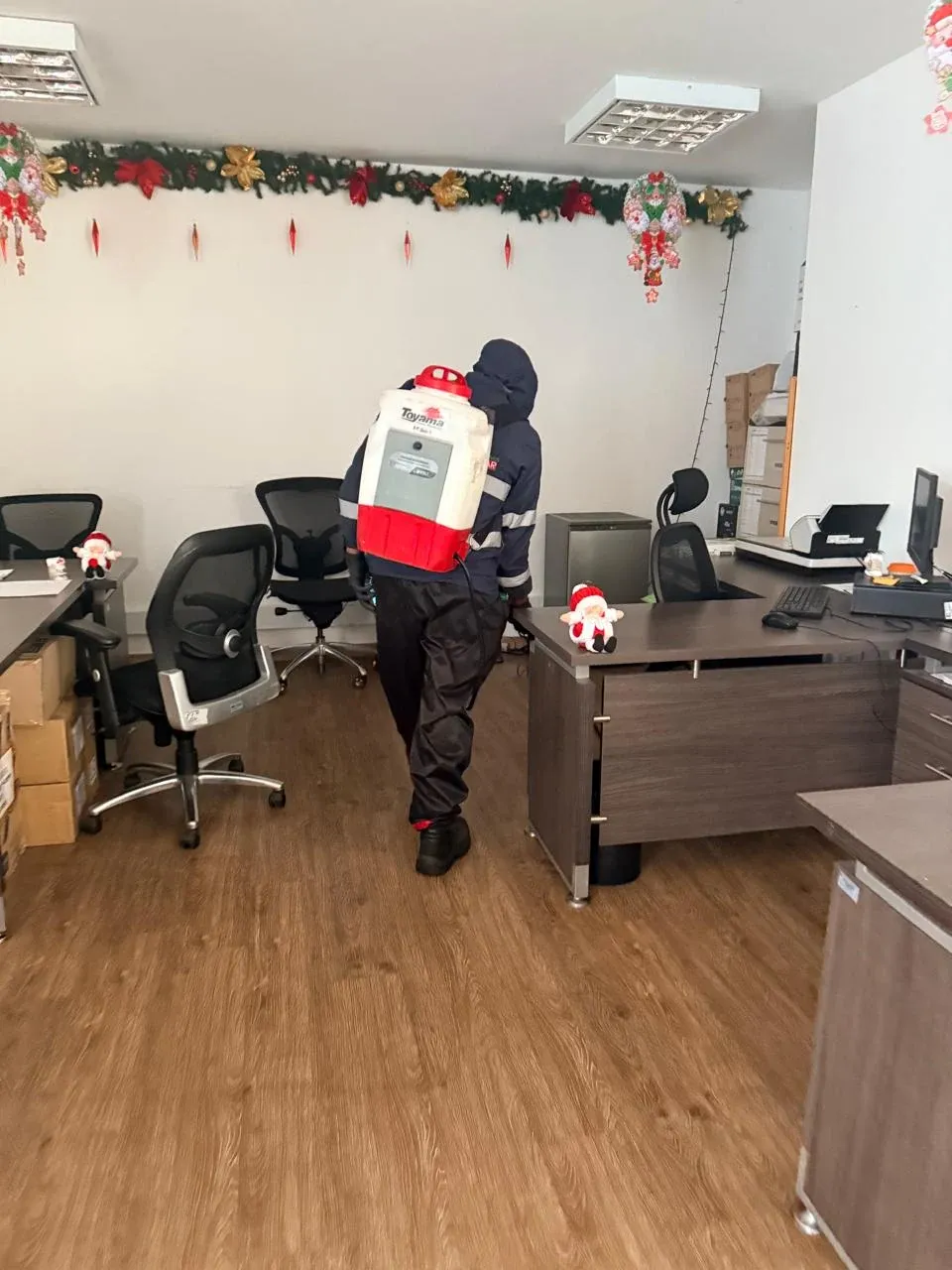 Técnico fumigando una oficina con escritorios y sillas en Bogotá