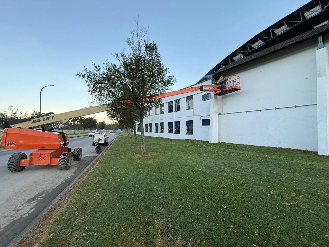 Plataforma elevadora trabajando en la fachada blanca de una bodega industrial en Bogotá