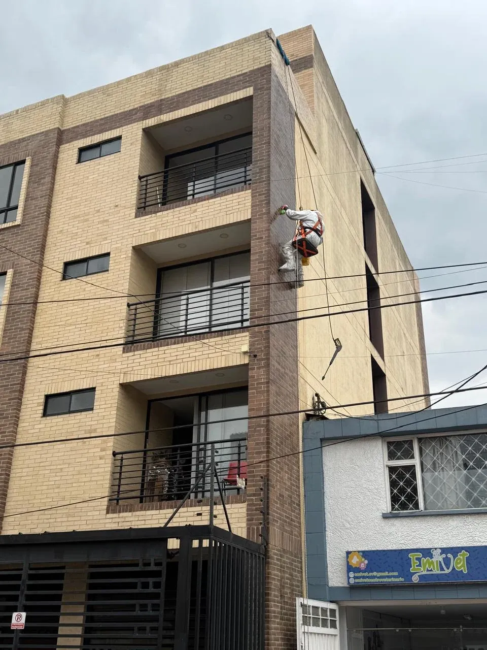 Técnico descolgado con cuerdas lavando la fachada de un edificio de apartamentos en Bogotá