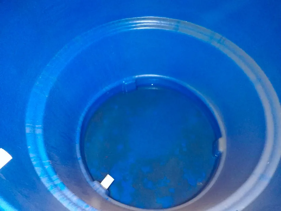 Tanque de agua azul con residuos y manchas en el fondo antes del lavado y la desinfección