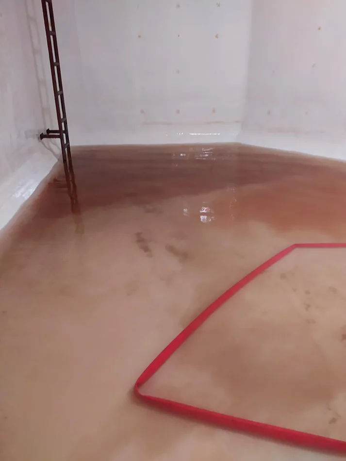 Tanque subterráneo con agua turbia de color café antes del lavado y la desinfección